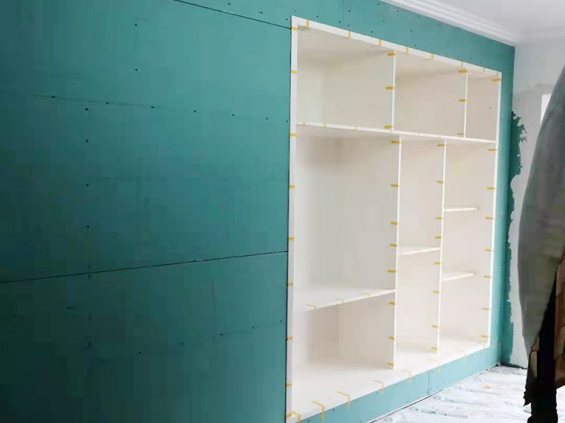 客廳定制柜體安裝：用墊布點好地板，先從靠墻的一端寬側板開始組裝，將寬側板平放于地面上（離后墻面保持700mm間隔）。首先將填好的三合一膠塞的板件，平放在墊布上，檢查孔距與圖紙相符，并裝上三合一單連桿。然后將固層釘上木塞，固定于寬側板上面，頂板大柄孔朝上，其余固層都朝下，腳線大柄孔朝內（中間固層與L架高度一致，即底板到固層內空為960mm，現場打層板孔）。放上側板，釘上木塞，木塞要求連通兩邊的固層。在第二個柜固層上面裝好雙連桿，留意雙連桿上面大柄只能鎖住一半，即90°。當兩件固層與側板固定后再同時擰緊大柄。裝第三個柜時重復第二個柜的安裝步驟。